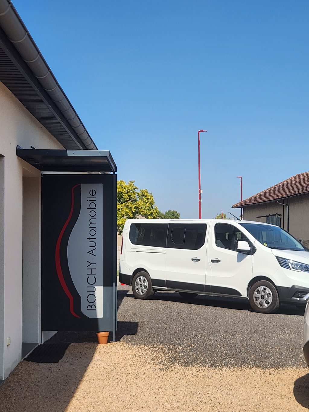 Le minibus 9 places devant l'enseigne Bouchy Automobiles